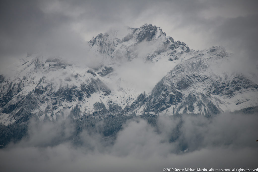 Snow-covered Alpine ridge partly obscured by low cloud and mist above Lucerne.