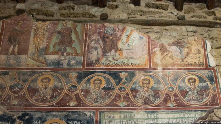 Wall fresco with upper narrative scenes, a row of linked haloed medallion portraits, and an inscription panel below.