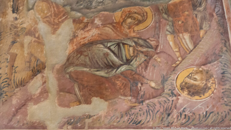 Damaged fresco fragment with a reclining haloed figure and partially preserved surrounding figures.