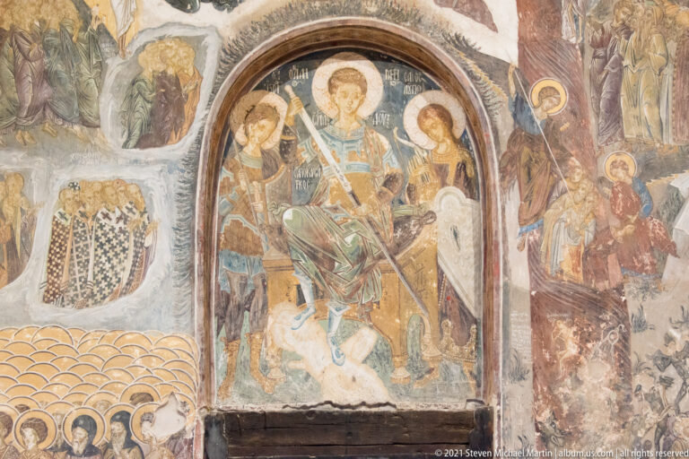 Arched fresco of an enthroned haloed figure flanked by attendants, surrounded by additional sacred wall paintings.