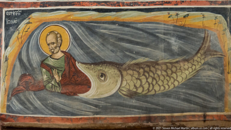 Haloed Jonah emerging from the open mouth of a large scaled sea creature against dark stylized water.
