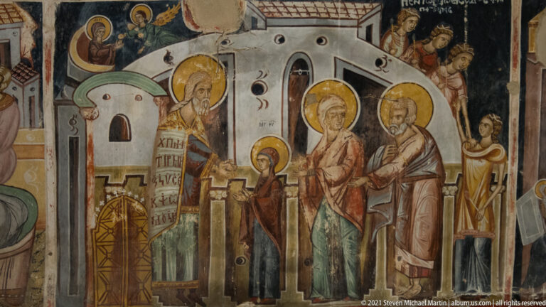 Small child between haloed adults in a ceremonial fresco set before stylized church or temple architecture.