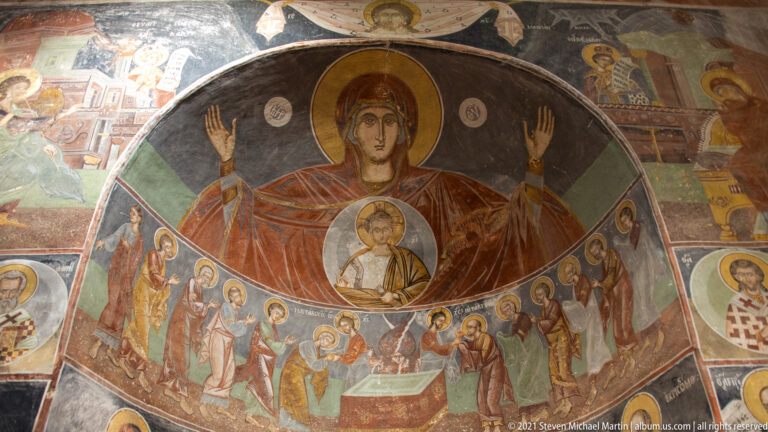 Apse mural of the praying Virgin with Christ in a medallion above rows of clerical and saintly figures.