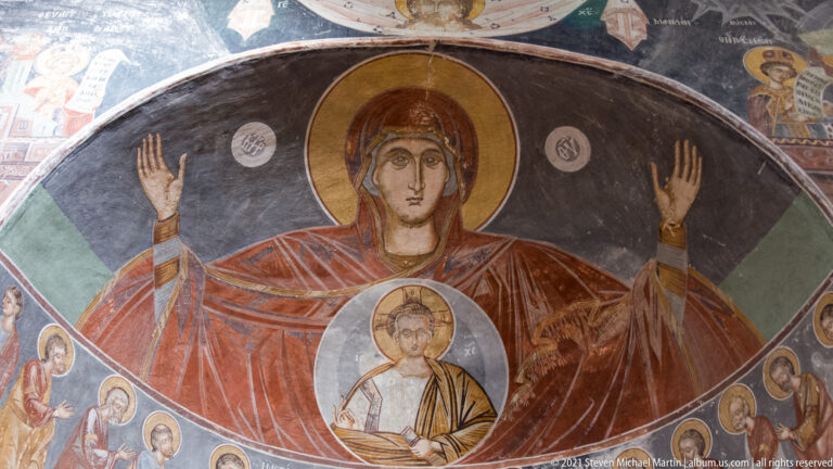 Close view of the Virgin with raised hands and the haloed Christ Child in a circular medallion.