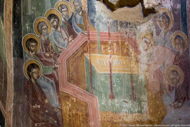 Haloed figures surround a tall stepped painted structure in a weathered narrative fresco.