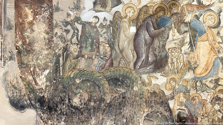 Weathered fresco with haloed figures and an angel above large dark reptilian or serpentine beasts.