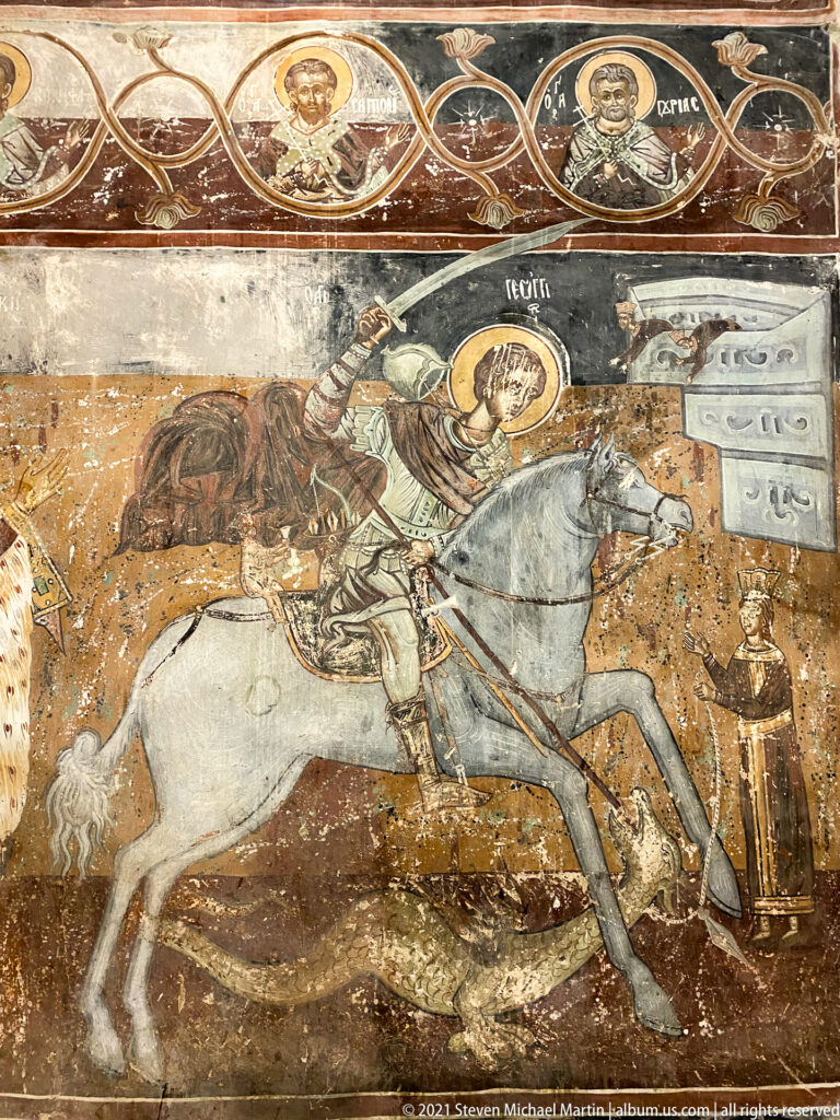 Haloed mounted warrior saint riding a white horse with a long lance beneath saint medallions.