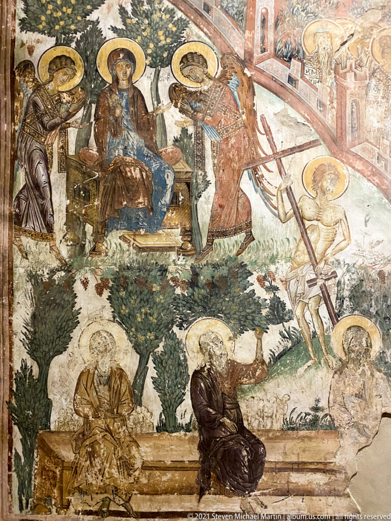 Continuous fresco narrative with haloed figures, trees, buildings, and several distinct episodes across one wall.
