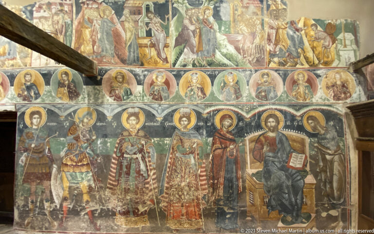 Rows of standing haloed saints and enthroned Christ beneath circular saint medallions and upper narrative scenes.