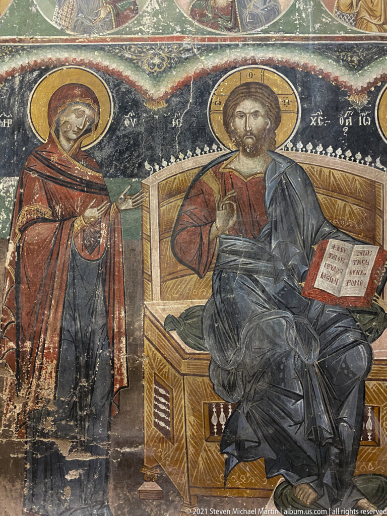 Enthroned Christ with cross halo, raised blessing hand, and open Gospel beside a standing female saint.