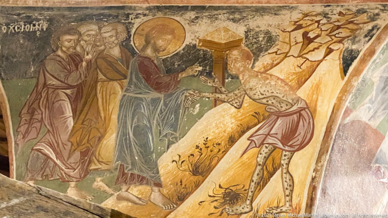 Haloed figure and attendants facing a nearly nude spotted man beside a small shrine-like structure.