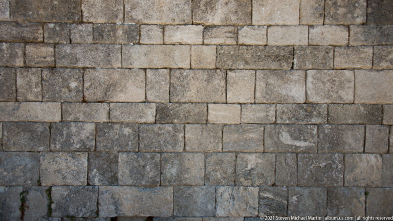 Close view of a wall built from regular rectangular stone blocks with weathered joints.