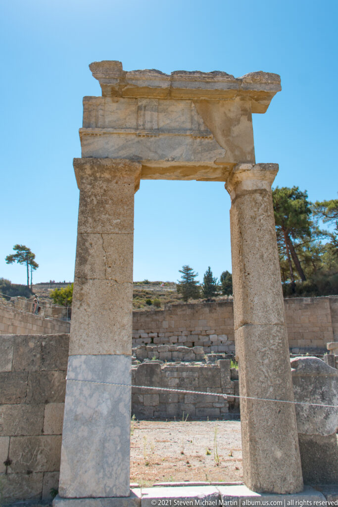 Two tall stone supports with restoration patches carrying a broad horizontal lintel against blue sky.