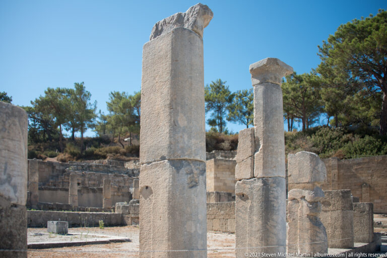 Close view of tall partially restored stone columns rising above the excavated ruins.