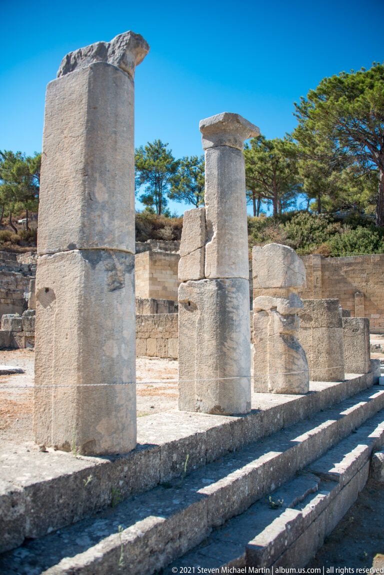 Angled view of restored stone columns on a raised platform with parallel steps in front.