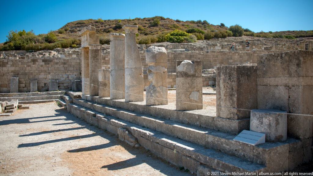 Oblique view of restored columns casting long shadows across a stepped stone terrace.