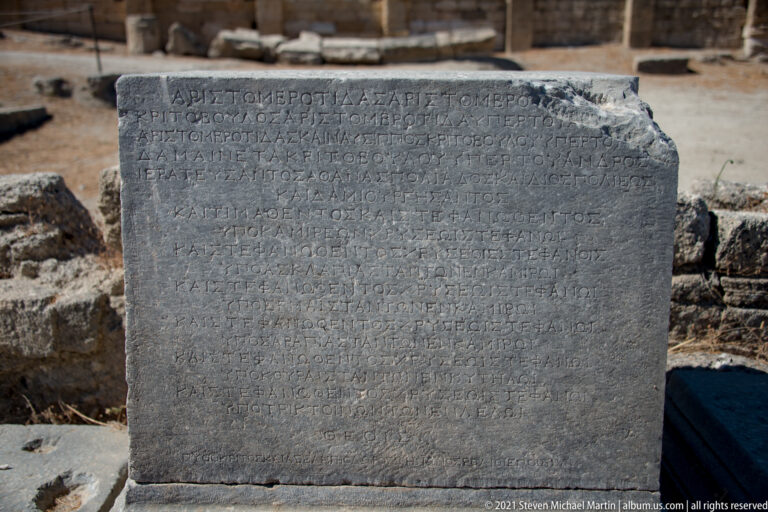 Large rectangular stone block covered with many lines of weathered Greek inscription.