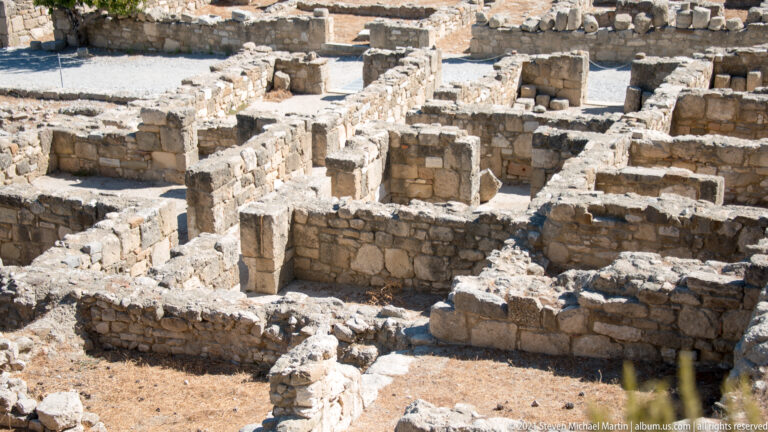 Dense cluster of excavated stone rooms with door openings, wall junctions, and varying floor levels at Ancient Kamiros.