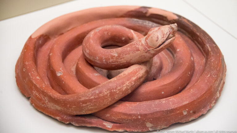 Red terracotta coil arranged in a tight spiral within a shallow round base.