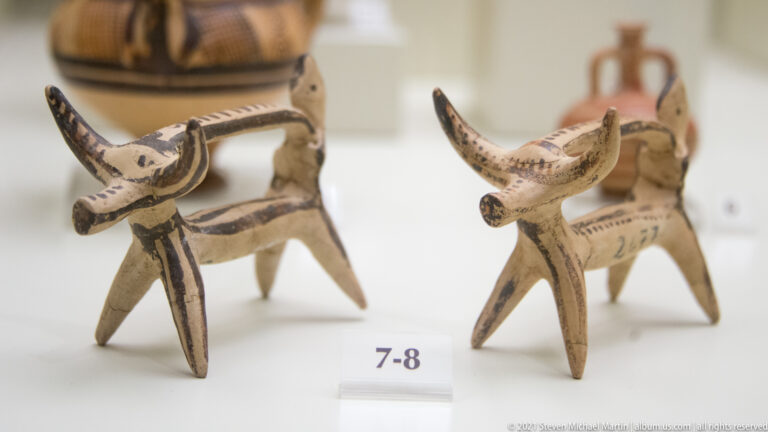 Two small four-legged terracotta animal figurines with long necks and dark painted linear decoration.