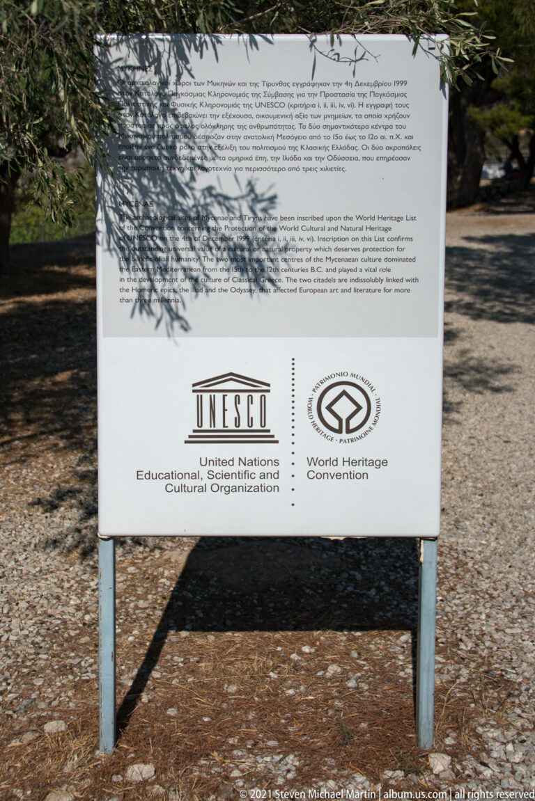 Outdoor UNESCO information panel at Mycenae with World Heritage logos and multilingual text.