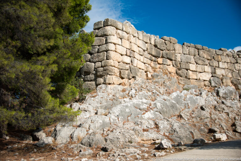 Close exterior view of large Cyclopean stone blocks rising directly from jagged limestone bedrock.