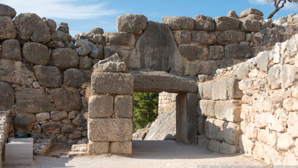 Rectangular stone doorway with massive jambs, lintel, and triangular relieving space within thick masonry.