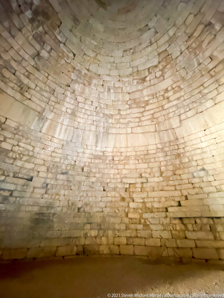 Curved interior wall of a Mycenaean tholos tomb built from tightly fitted corbelled stone courses.