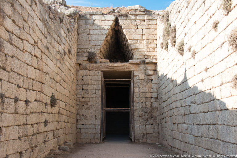 Frontal view down the ashlar-lined dromos to the lintelled entrance and relieving triangle of the Tomb of Clytemnestra.
