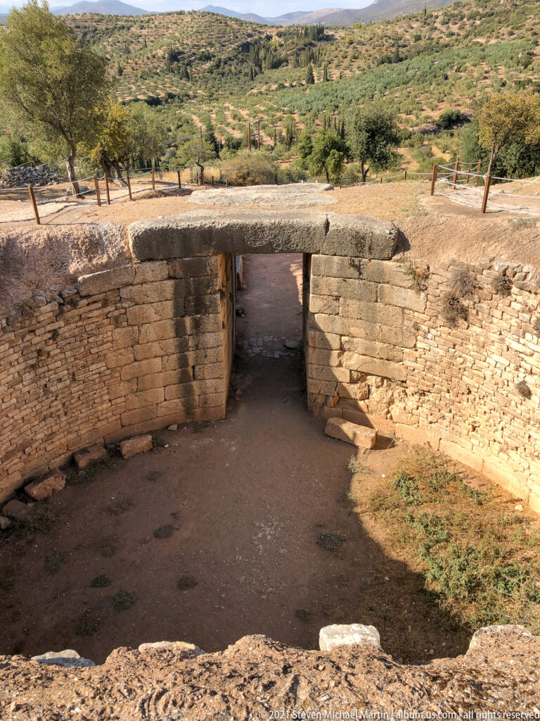Interior of the Tomb of Clytemnestra looking through its massive doorway toward the sunlit dromos.
