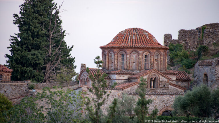 Hagia Sophia at Mystras with tiled dome, brick arches, stone masonry, and surrounding ruins.