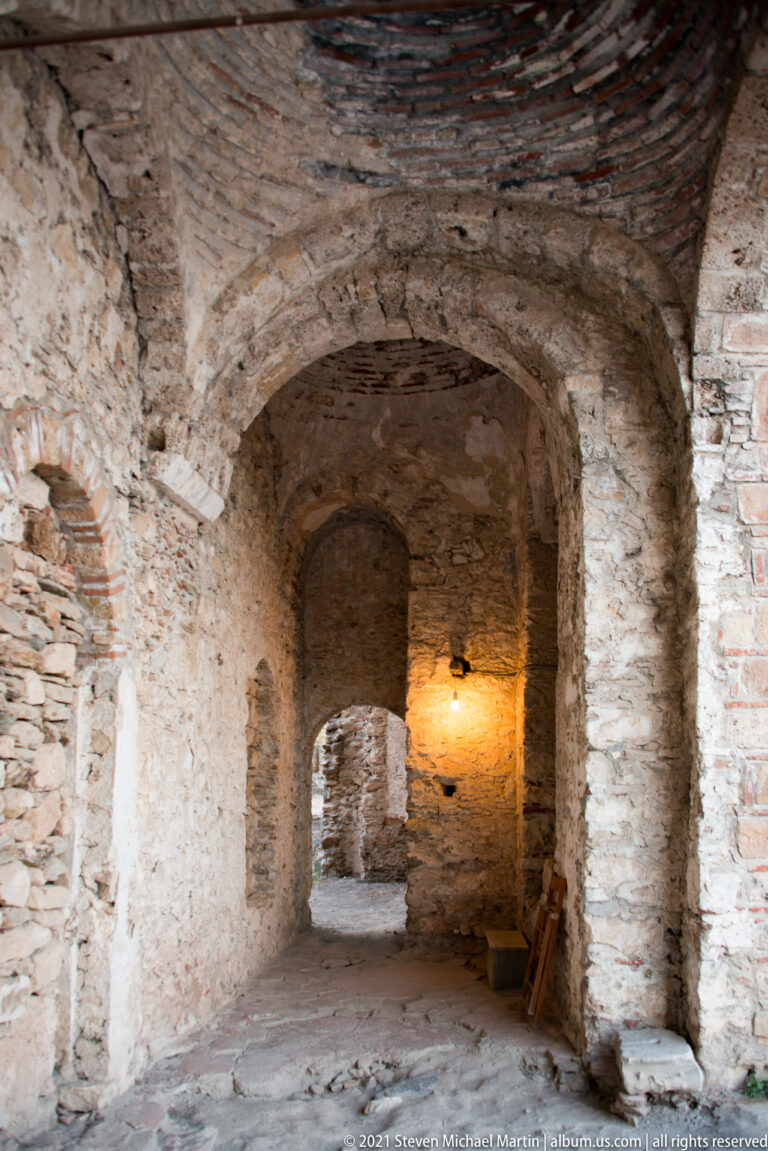 Narrow vaulted passage inside St. Sophia at Mystras with successive masonry arches and exposed stonework.