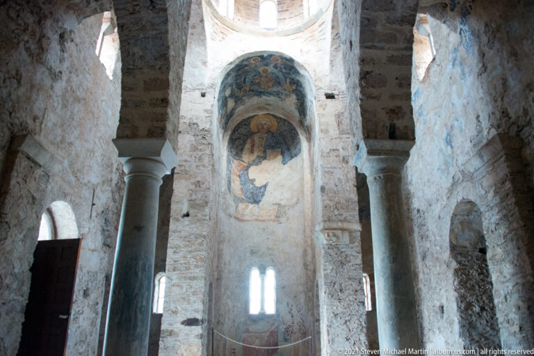 Tall columns and arches frame the frescoed recess and dome windows inside St. Sophia at Mystras.