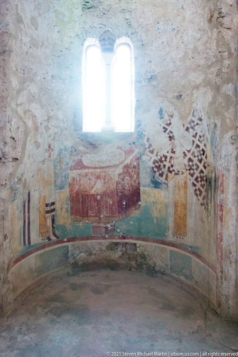 Fragmentary frescoes beneath a twin-light window in St. Sophia, including a large red central form and partial robed figures.