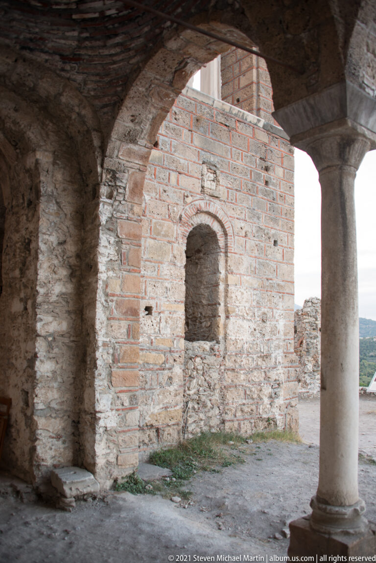Stone column and broad arch beside a brick-and-stone wall with a small arched recess at St. Sophia.