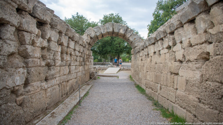 View from inside the stone-walled Krypte through its arched opening toward the Stadium of Olympia.