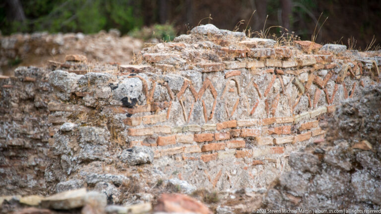Close view of ancient brick wall with repeated diagonal chevron or herringbone patterns between horizontal courses.