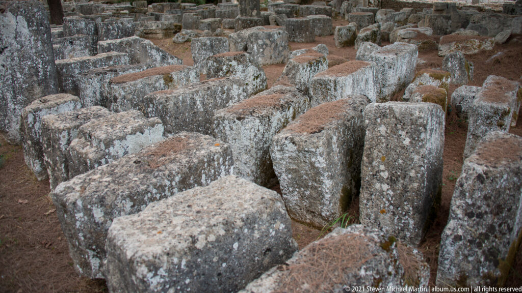 Close view of numerous weathered stone column drums clustered upright and on their sides.