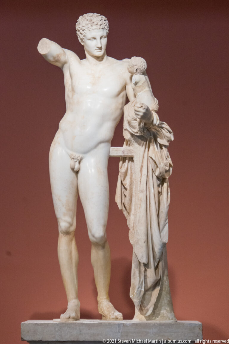 Hermes carrying the infant Dionysus, traditionally attributed to Praxiteles, standing beside a draped tree-trunk support.