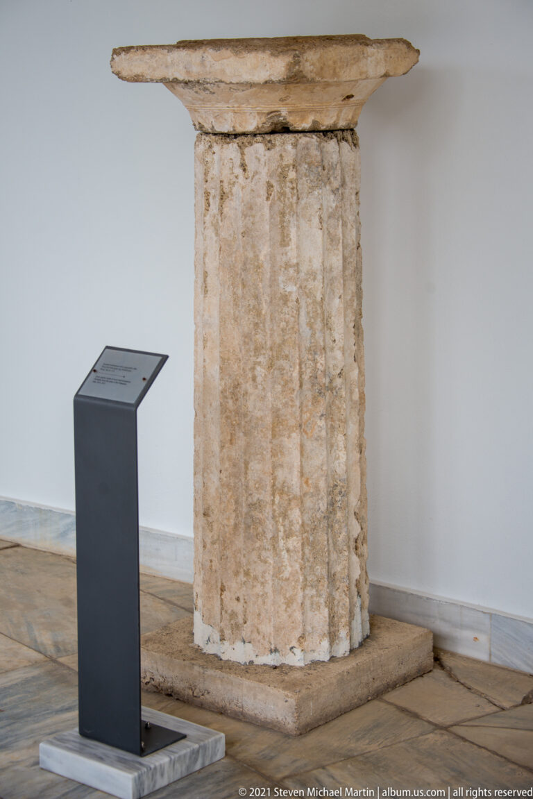 Weathered upright stone architectural member with vertical fluting and a broad square block at the top.