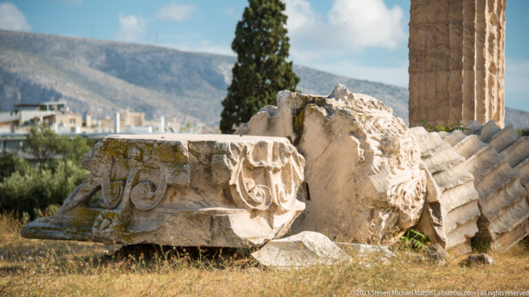 Fallen Corinthian capital and fluted marble column drums beside a standing column at the Temple of Olympian Zeus.
