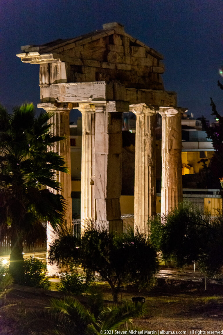 Illuminated four-column Doric Gate of Athena Archegetis with triangular pediment in the Roman Agora at night.