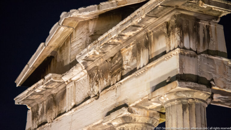Close night view of weathered Doric entablature, cornice, and column capitals on the Gate of Athena Archegetis.
