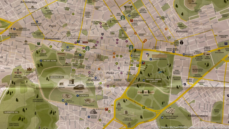 Tourist map of central Athens showing the Acropolis, Plaka, Monastiraki, parks, museums, roads, and archaeological sites.