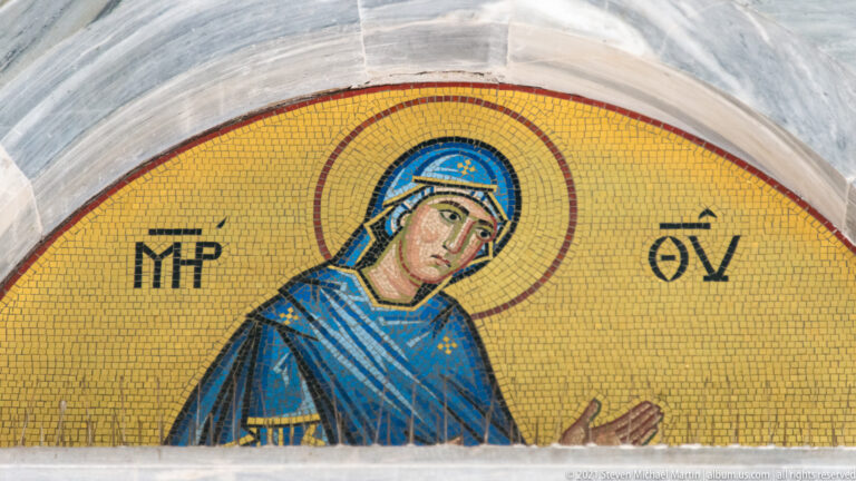 Gold-ground mosaic of the Virgin Mary in blue robes with Greek abbreviations beside her halo.