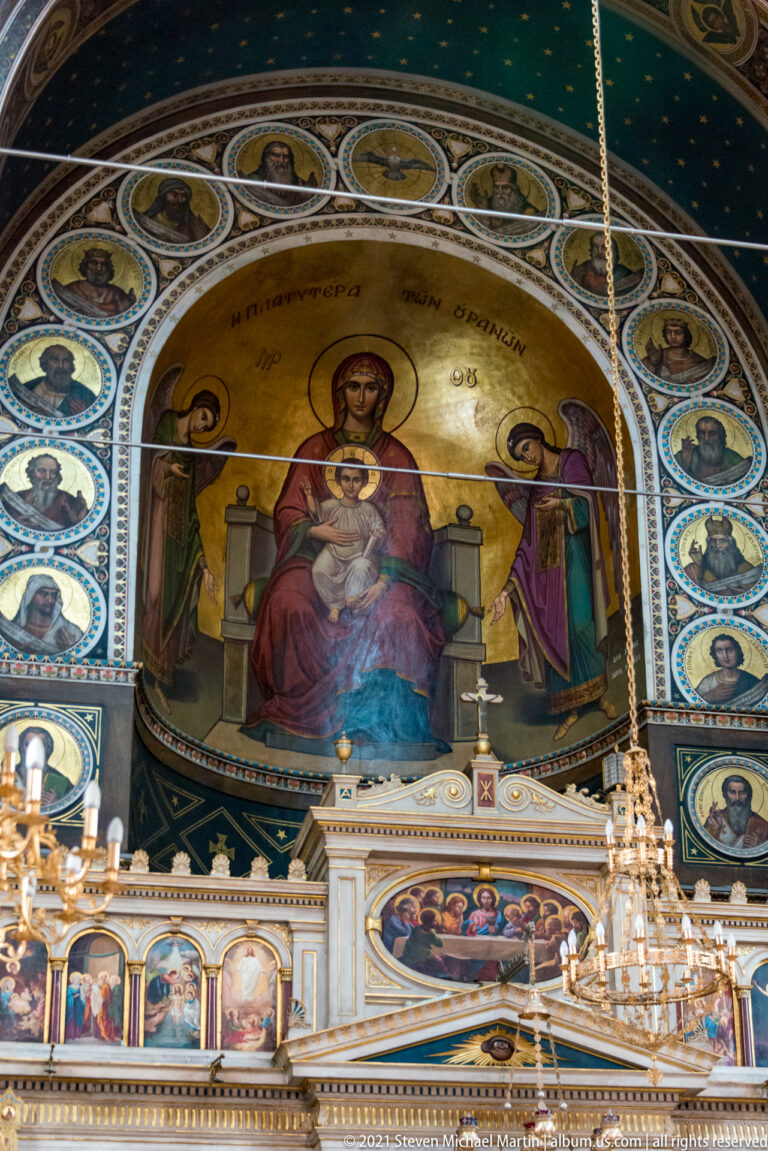 Enthroned Virgin and Child mural filling the apse above rows of saint medallions and the sanctuary furnishings.