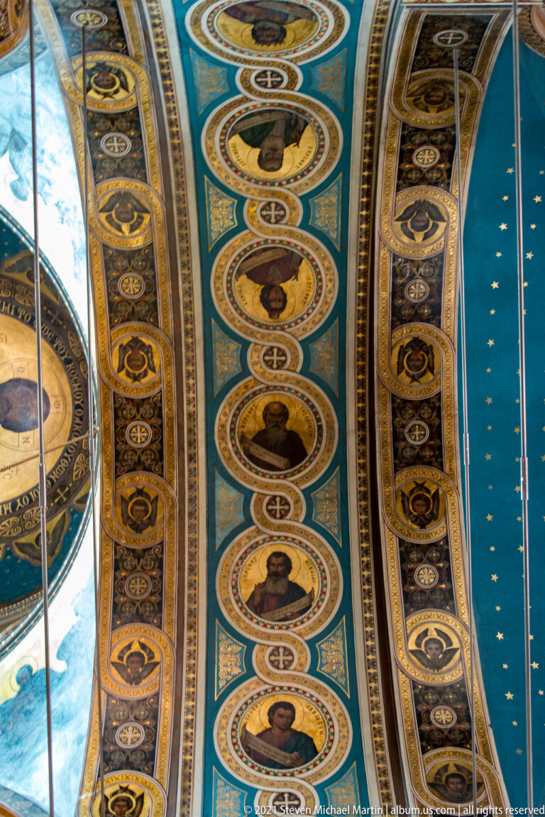 Parallel blue church vaults covered with rows of circular saint portraits and patterned painted borders.