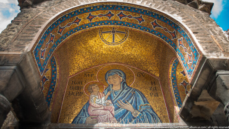 Virgin and Child mosaic framed by a blue, red, and gold patterned arch in the stone entrance of Panagia Kapnikarea.