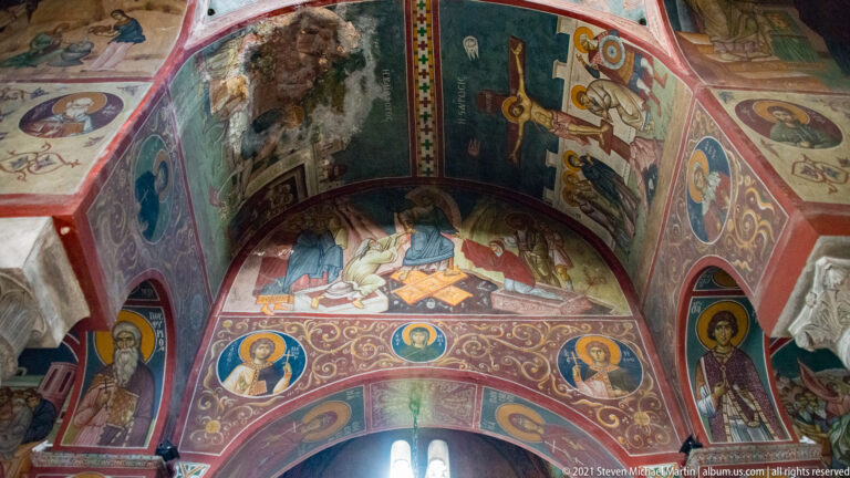 Vaulted interior of Panagia Kapnikarea densely covered with biblical fresco scenes, saint portraits, crosses, and painted borders.