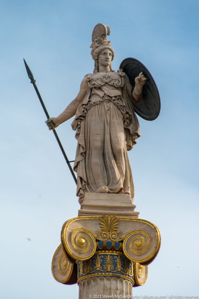 Helmeted Athena holding spear and shield atop a brightly painted Ionic column at the Academy of Athens.